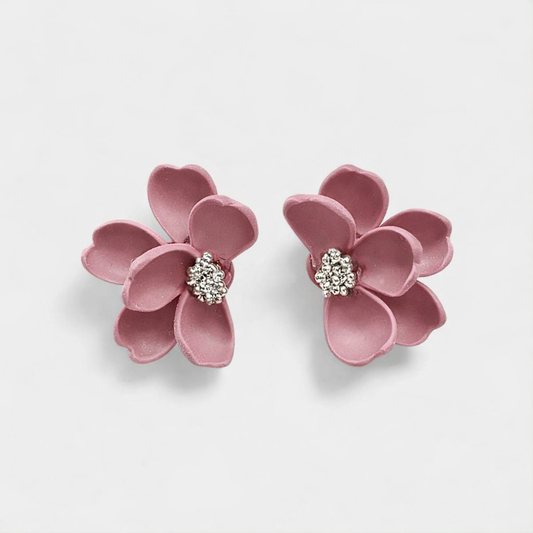 Pink flower-shaped earrings with a central gemstone on a light gray background